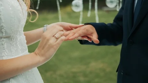 Wedding couple put on wedding rings at ceremony outdoors at summer sunny day Stockbeeldmateriaal 114986652