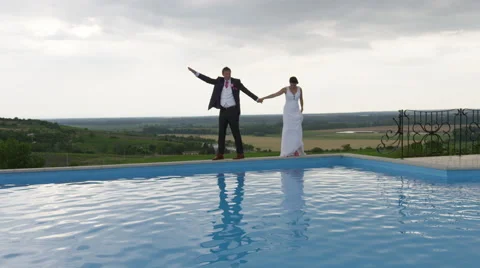 Wedding Couple Walks Edge Pool View - 4k - Slow Motion Stock Footage 53077683
