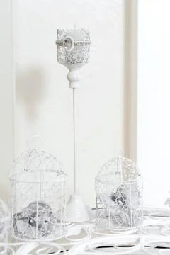 Wedding decor. On a bright table is a candlestick, with two baskets of orids  Stock Photos