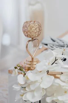 Wedding decor. On a bright table is a candlestick, with two baskets of orids  Stock Photos