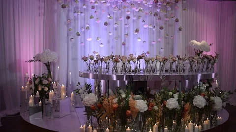 Wedding decor. Burning candles on background of roses in vases are on table. Stock Footage 127914048
