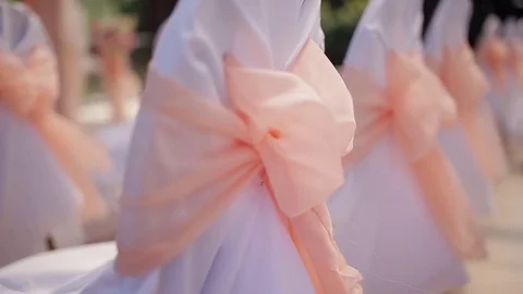 Wedding decor on the chairs.  White wedding chairs with pink ribbon bow. Outdoor Stock Footage 84273463