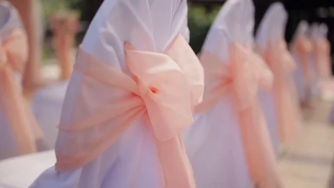 Wedding decor on the chairs.  White wedding chairs with pink ribbon bow. Outdoor Stock Footage 84273464