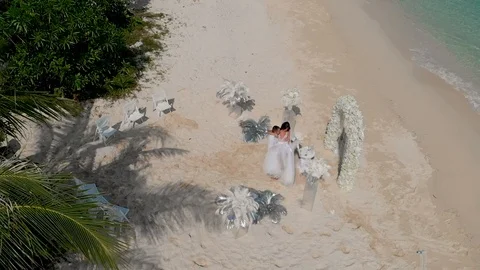 Wedding decorations on the ocean beach shot from the sky. the groom circles the  Stock Footage 116432557