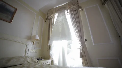 Wedding dress hanging on a window Stock Footage 32859845