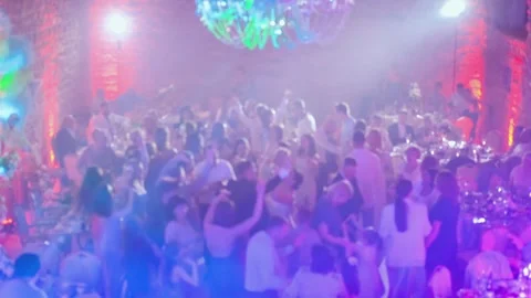 The wedding guests all dance together raising their hands in the air. Blurred Stock Footage 243680144