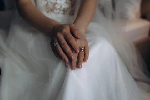 Wedding hands clasped gently over a gown's hem Foto stock
