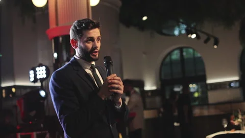 Wedding host with microphone speaking in front of audience Video stock 250086010
