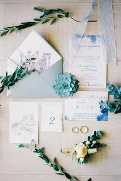Wedding invitations on the table next to wedding rings and flowers Stock Photos