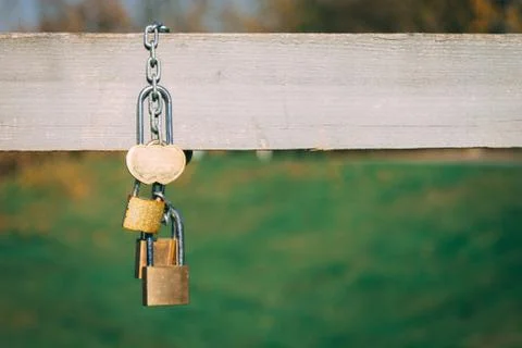 Wedding locks with a heart shape hanging on an iron chain on a w Stock Photos