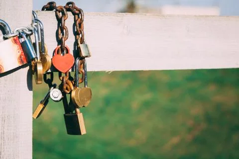 Wedding locks with a heart shape hanging on an iron chain on a w Stock Photos