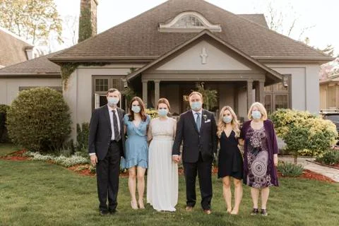 Wedding party posing for group portrait on front lawn, wearing face masks during Stock Photos