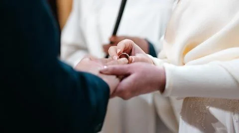 Wedding ring and hands of bride and groom, young wedding couple at ceremony in Stock Photos