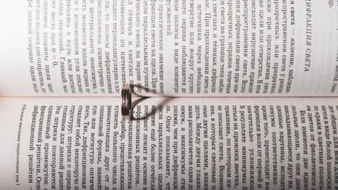 Wedding ring between the pages of an book with the sunlight casting a heart Stock Photos