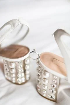 Wedding ring between wedding shoes and highlights Stock Photos