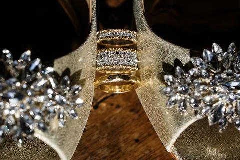 Wedding ring between wedding shoes and highlights Stock Photos