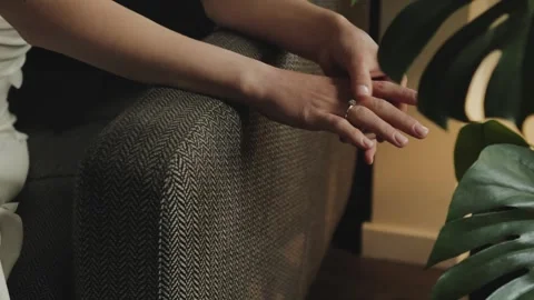 Wedding ring on the brides hand. The brides hands, sitting on the sofa, touch Stock Footage 315947989