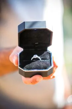 Wedding ring with diamonds in black elegant box. Man holds an open jewellery box 写真素材