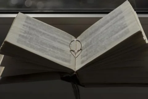 Wedding ring with a falling shadow in the form of a heart standing on an open Stock Photos