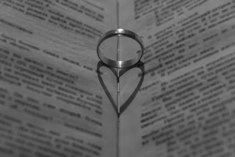 Wedding ring with a falling shadow in the form of a heart standing on an open Stock Photos