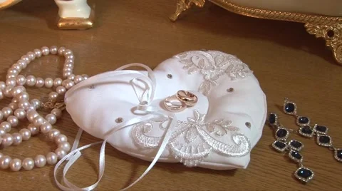 Wedding ring lies on a bed in a heart next to the other decorations Stock Footage 55795688