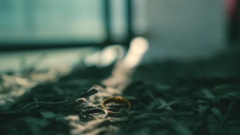 The wedding ring lies on a gray carpet in a ray of sunshine Video stock 226349432