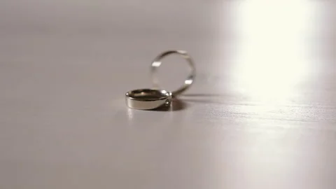 The wedding ring rides across the table and falls next to the diamond ring Stock Footage 149003558
