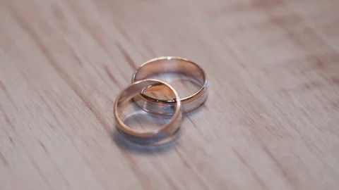 Wedding rings and play with the light on the wooden background Stock Footage 129094050