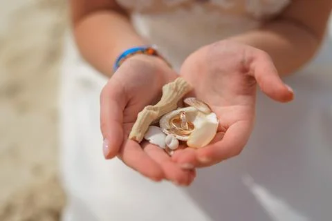 Wedding rings and small shells in the hands of a girl. Stock Photos