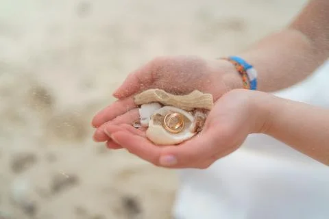 Wedding rings and small shells in the hands of a girl. 스톡 사진