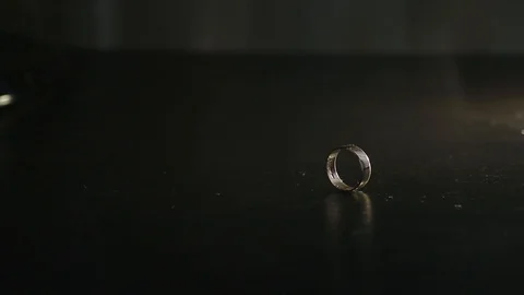 Wedding rings on black mirrored surface shining with light and rolling together. Stock Footage 120154749