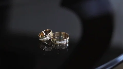 Wedding rings on a black transparent table in reflection Stock Footage 80023723