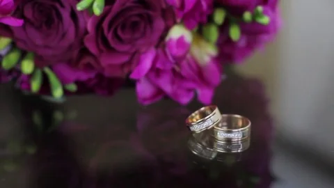 Wedding rings on a black transparent table in reflection with a wedding bouquet Stock Footage 80023772
