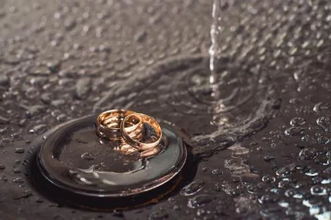Wedding rings on a chrome plated surface. water drops with reflections of light Stock Photos