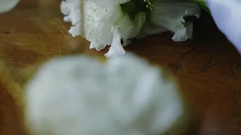 Wedding rings displayed on white flower inside glass box on wooden table Видео 338399245