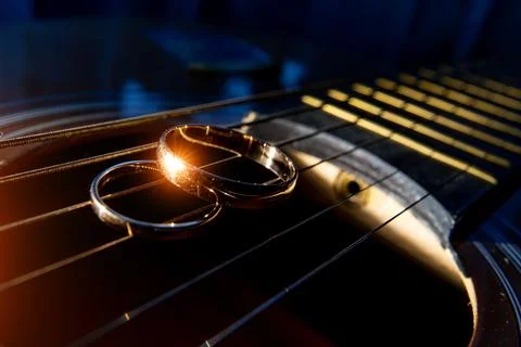 Wedding rings on guitar strings close-up on a dark background. 스톡 사진