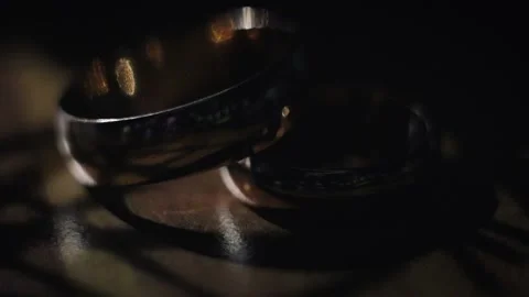Wedding rings lie on the table and glow on a dark background, close-up Stock Footage 104487557