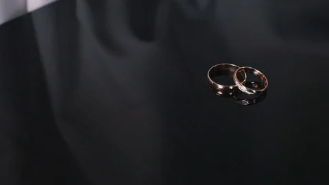 Wedding rings lying on a dark surface with reflection. Shining light macro close Stock Footage 108635610
