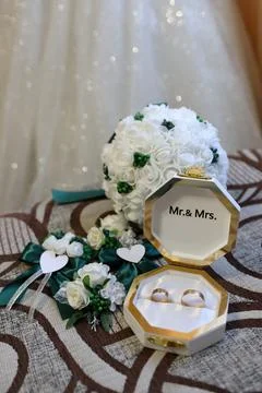Wedding rings in an open gift box beside the bridal bouquet and wedding acces Photos