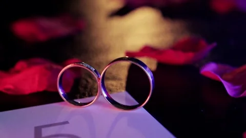 Wedding rings under different lighting and colored lights on the table, close-up Stock-Footage 304110932