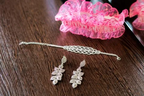 The wedding set on the table. Earrings and garter on the wood 库存照片