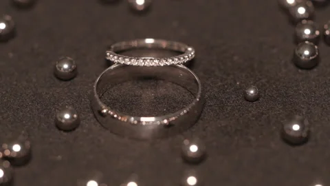 Wedding silver rings lying on shiny shining surface with light, close-up macro f Video stock 169938621