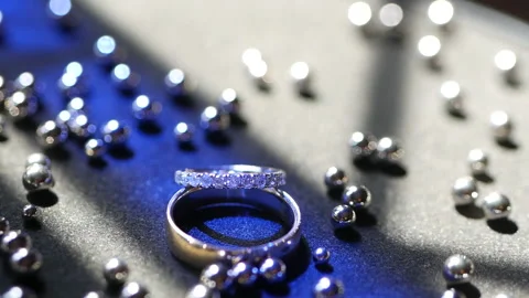 Wedding silver rings lying on shiny shining surface with light, close-up macro f Video stock 169938994