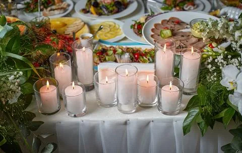 Wedding table with candles, white tablecloth, various food and flowers, sel.. Stock Photos
