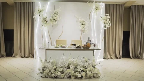 A wedding table decorated with flowers at which the newlyweds are sitting Stock Footage 327982206