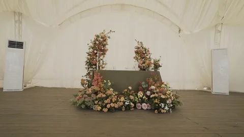 A wedding table decorated with flowers at which the newlyweds are sitting Vídeo Stock 328314672