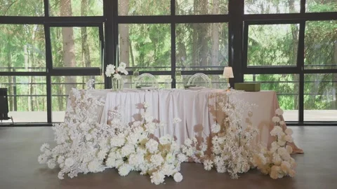 A wedding table decorated with flowers at which the newlyweds are sitting Stock Footage 329092747
