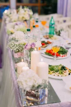 The wedding table set covered with different dishes and candles. Stock Photos
