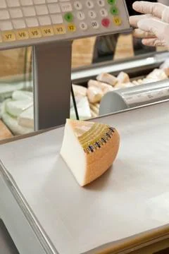 A wedge of cheese being weighed on a delicatessen scale Stock Photos