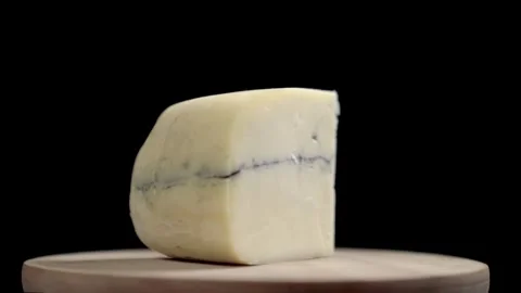 A wedge of Morbier cheese rotating with a black background Stock Footage 241504730
